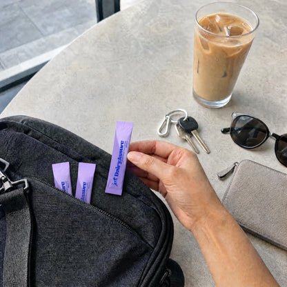DairyAssure lactase sticks packed beside an iced coffee for on-the-go use