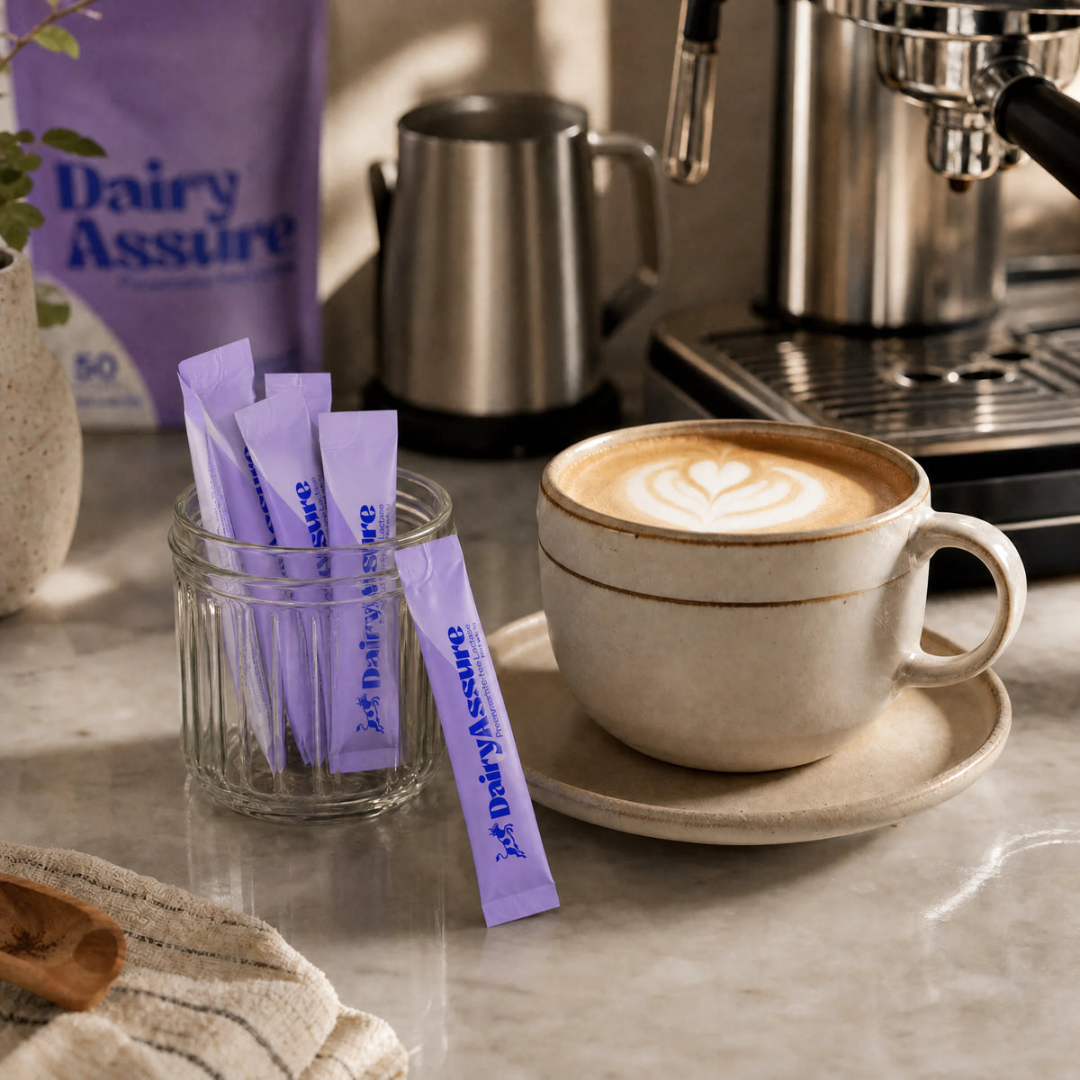 Five DairyAssure lactase sticks beside a latte at a coffee station
